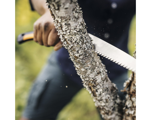 Eine Person sägt einen Baumstamm mit einer Handsäge.