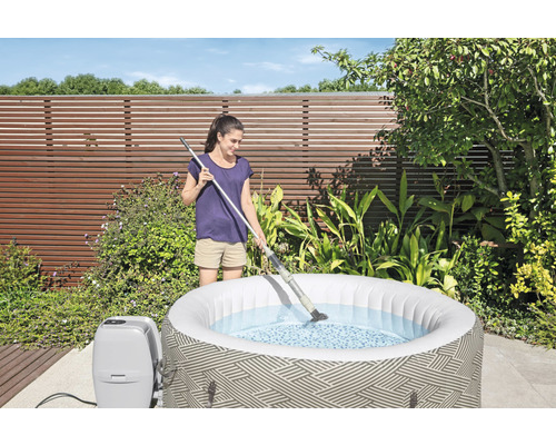 Frau reinigt aufblasbaren Whirlpool im Garten mit einem Poolreiniger
