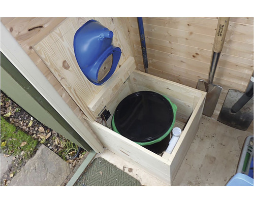 Innenansicht eines Holzschuppens mit Komposttoilette und Gartengeräten