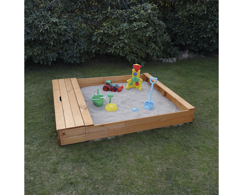 Holzsandkasten mit Spielzeug auf einer Rasenfläche