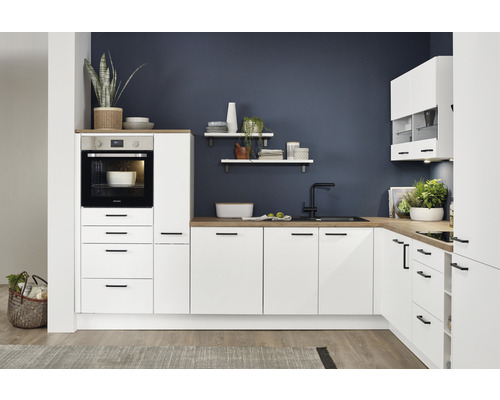 Helle Küche mit Einbaubackofen, Spüle, Arbeitsplatte und Hängeschränken vor dunkler Wand