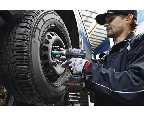 Ein Mechaniker verwendet einen Akku-Schlagschrauber, um die Radmuttern an einem Autoreifen zu befestigen