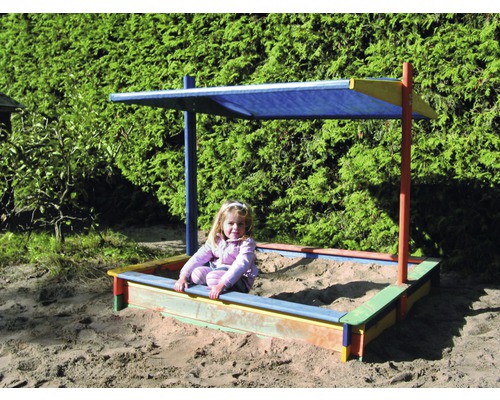 Kind im Sandkasten mit Sonnenschutz im Garten