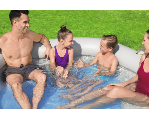 Familie entspannt in einem aufblasbaren Whirlpool im Garten.