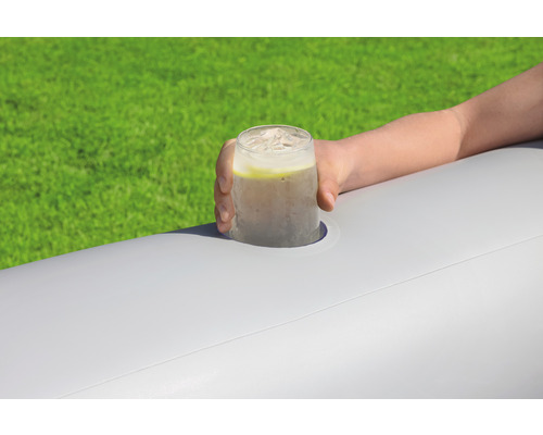 Hand hält ein Getränk mit Eiswürfeln in einem Getränkehalter auf einer aufblasbaren Oberfläche