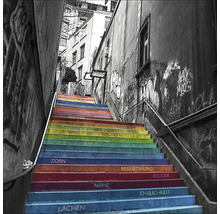 Treppe mit Regenbogenfarben und aufgemalten Wörtern zwischen Gebäuden