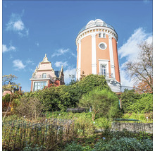 Turm und Gebäude in einem Garten mit Pflanzen und Büschen