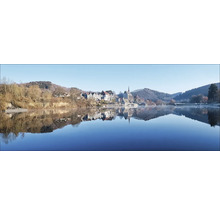 Panoramaaufnahme eines Sees mit einem Dorf und Wäldern im Hintergrund