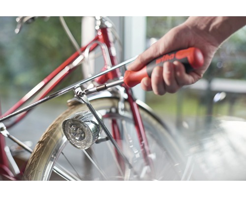 Eine Person befestigt mit einem Schraubendreher die Lampe an einem Fahrrad.