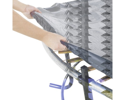 Detailaufnahme eines Trampolins mit Federn und Abdeckung, die von einer Hand gehalten wird.