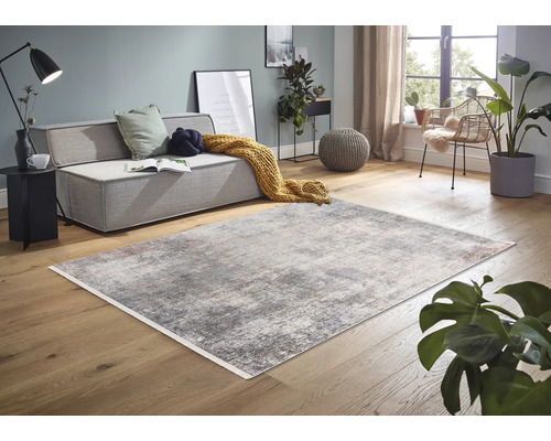 Wohnzimmer mit Sofa, Sessel und abstraktem Teppich auf Holzboden