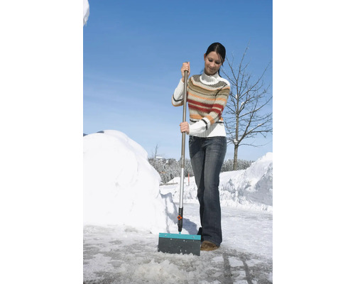 Frau räumt Schnee mit einem Schneeschieber.