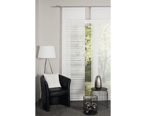 Wohnzimmer mit Schiebegardinen, Sessel, Stehlampe und Dekorationsgegenständen für ein gemütliches Ambiente.