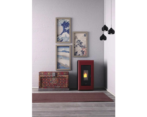 Wohnzimmer mit Pelletkaminofen, Truhe, Teppich, Hängelampe und gerahmten Bildern an der Wand