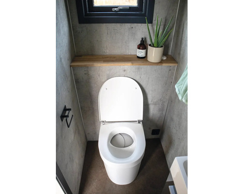 Toilette in einem Badezimmer mit Regal und Fenster