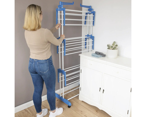 Frau stellt Wäscheständer auf. Wäschetrockner mit mehreren Ebenen, Wäschehängevorrichtung.