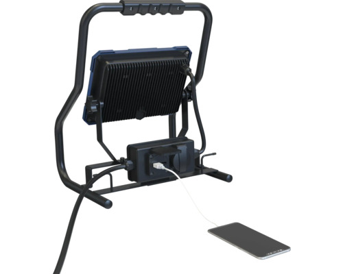 LED-Baustrahler mit Steckdose und geladenem Mobiltelefon