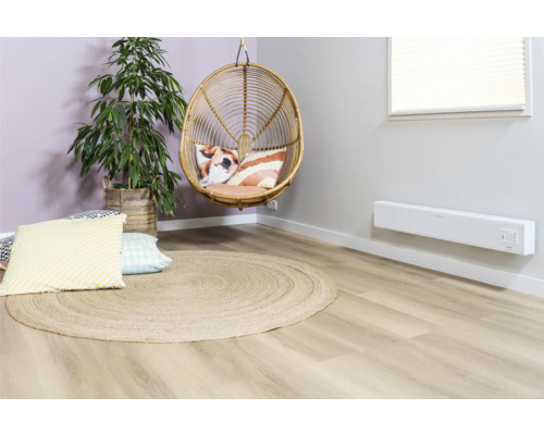 Wohnzimmer mit Rattansessel, runder Jute-Teppich, Zimmerpflanze und Wandheizung