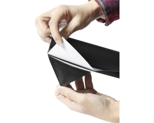 Person zieht Schutzfolie von selbstklebender Folie ab