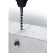 Ein Betonbohrer bohrt ein Loch in einen Betonblock.