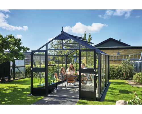 Familie sitzt in einem Gewächshaus im Garten.