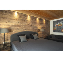 Schlafzimmer mit Holzwand, Bett, Nachttischen, Lampen und Sofa