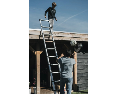 Szene im Freien mit einem Jungen auf einer Teleskopleiter und einem Mann mit einem Fußball.