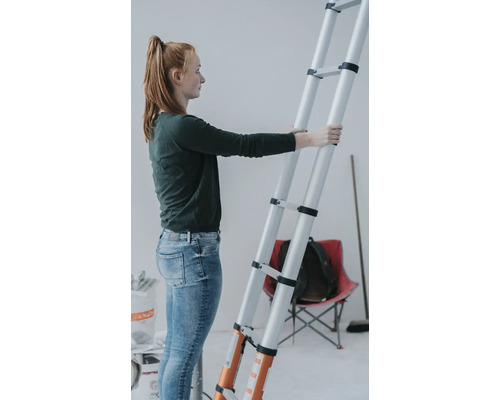 Frau hält eine Teleskopleiter in einem Raum.