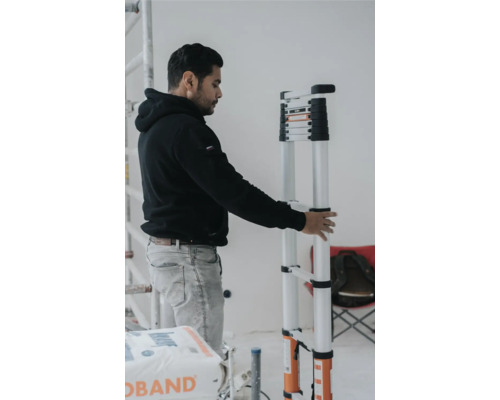 Mann hält eine Teleskopleiter in einem Innenraum