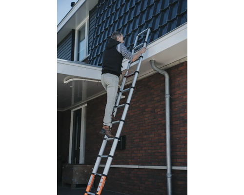 Mann steigt auf einer Teleskopleiter an einem Haus empor