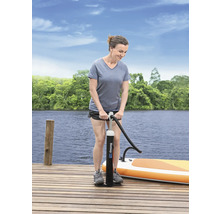 Frau pumpt ein Stand-Up-Paddleboard mit einer Handpumpe auf einem Holzsteg auf