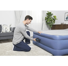 Mann pumpt eine aufblasbare Matratze mit einer Pumpe auf