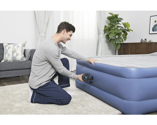 Mann pumpt eine aufblasbare Matratze mit einer Pumpe auf