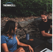 Szene im Freien mit Thermacell Mückenschutzgerät auf einem Tisch neben Personen