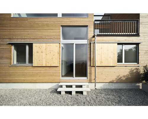 Fassade eines Hauses mit Holzverkleidung, Fenster und Schiebeläden