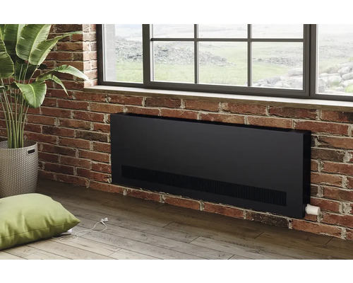 Schwarzer Heizkörper an Ziegelwand unter Fenster, mit Zimmerpflanze und Kissen im Raum.