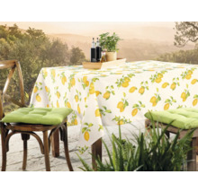 Gedeckter Tisch mit Tischdecke mit Zitronenmuster und Stühlen mit Kissen auf einer Terrasse