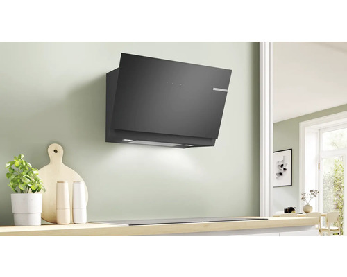 Dunstabzugshaube in einer Küche mit Kochfeld und Küchenutensilien.