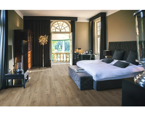 Schlafzimmer mit Bett, Schrank, Stehlampe und Balkon mit Blick auf einen Park.