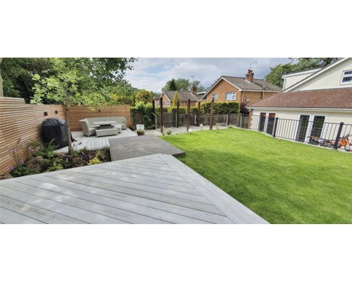 Garten mit Terrasse, Rasenfläche und Sitzbereich mit Grill.