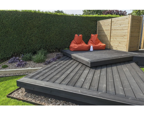 Gartenszene mit Holzterrasse, Sitzsäcken und Gartenzaun