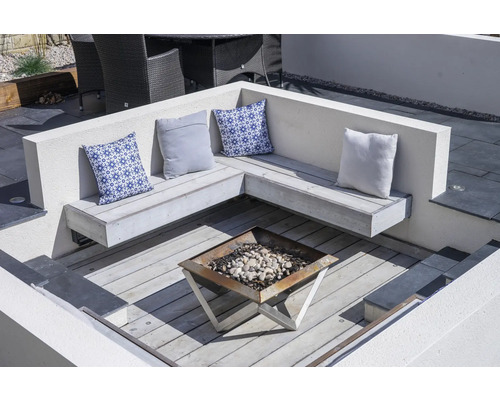 Gartenszene mit Sitzecke, Kissen und Feuerstelle