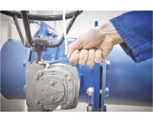 Ein Arbeiter bedient ein industrielles Ventil mit einem Schraubenschlüssel.