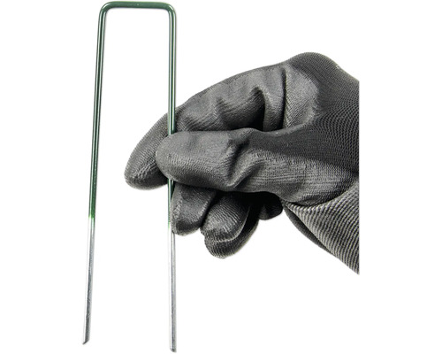 Eine Hand mit Gartenhandschuh hält einen grünen Rasen Nagel.