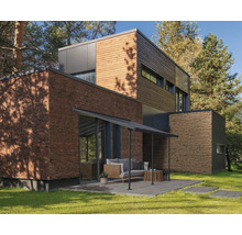 Modernes Haus mit Holzfassade, Backsteinmauer und Terrasse im Garten.
