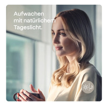 Frau mit Tasse am Fenster mit Tageslicht-Symbol