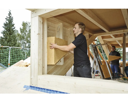 Handwerker bringt Dämmmaterial in einem Holzrahmenhaus an