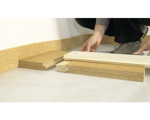 Szene von Personen, die Holzsockelleisten installieren