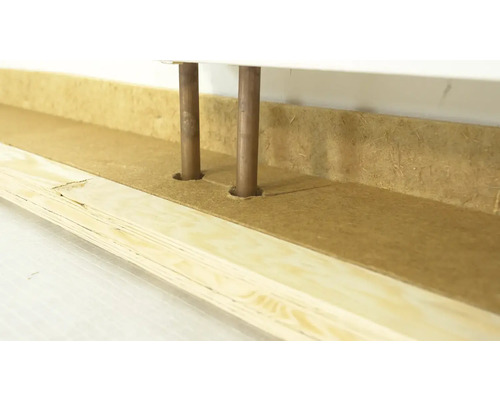 Detailansicht von Heizungsrohren, die durch eine Holzverkleidung verlaufen.