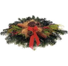 Gesteck mit Tannenzweigen, Zapfen und Schleife als weihnachtliche Dekoration
